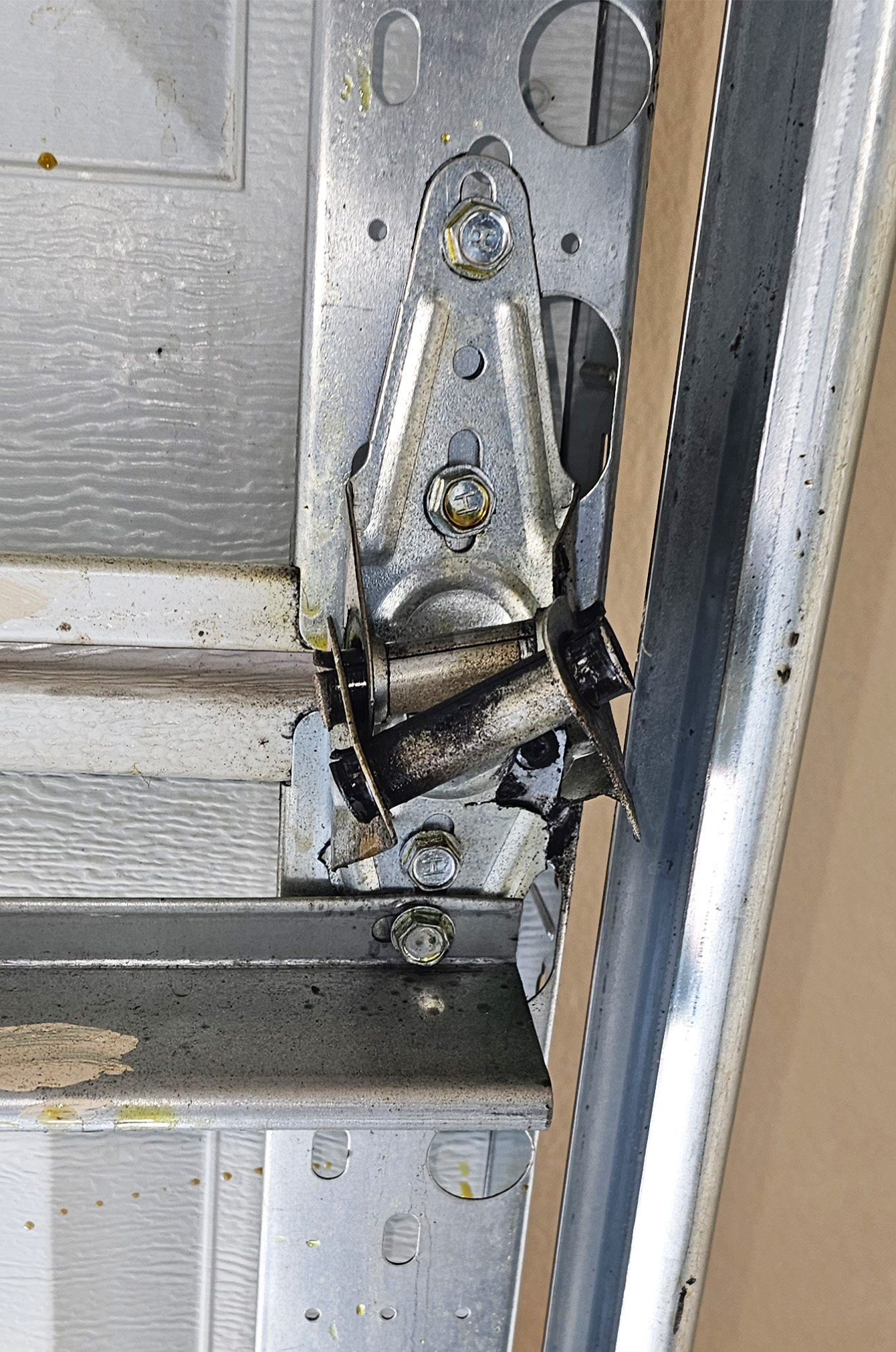 Broken garage door hinge pulling away from a residential garage door section