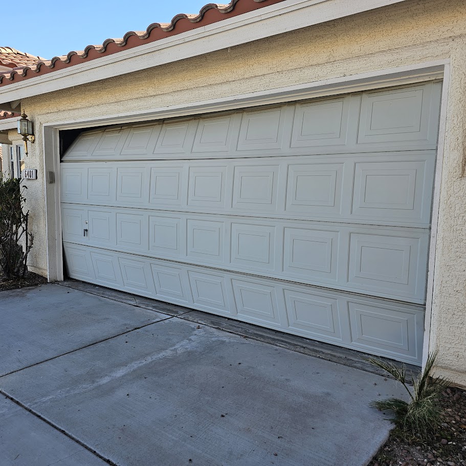 Dented and crooked residential garage door with visible impact damage