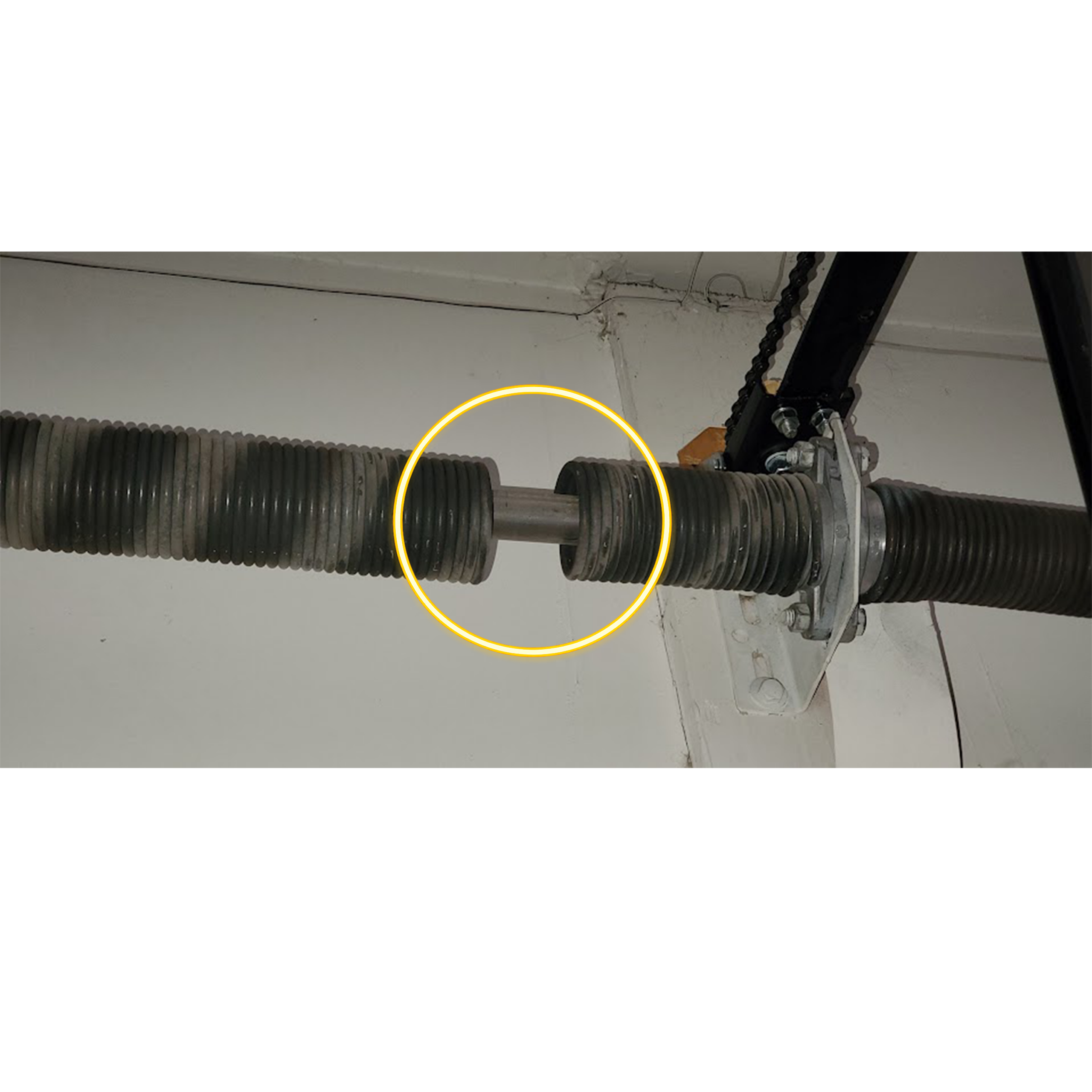 Broken standard torsion spring with a visible gap above a residential garage door