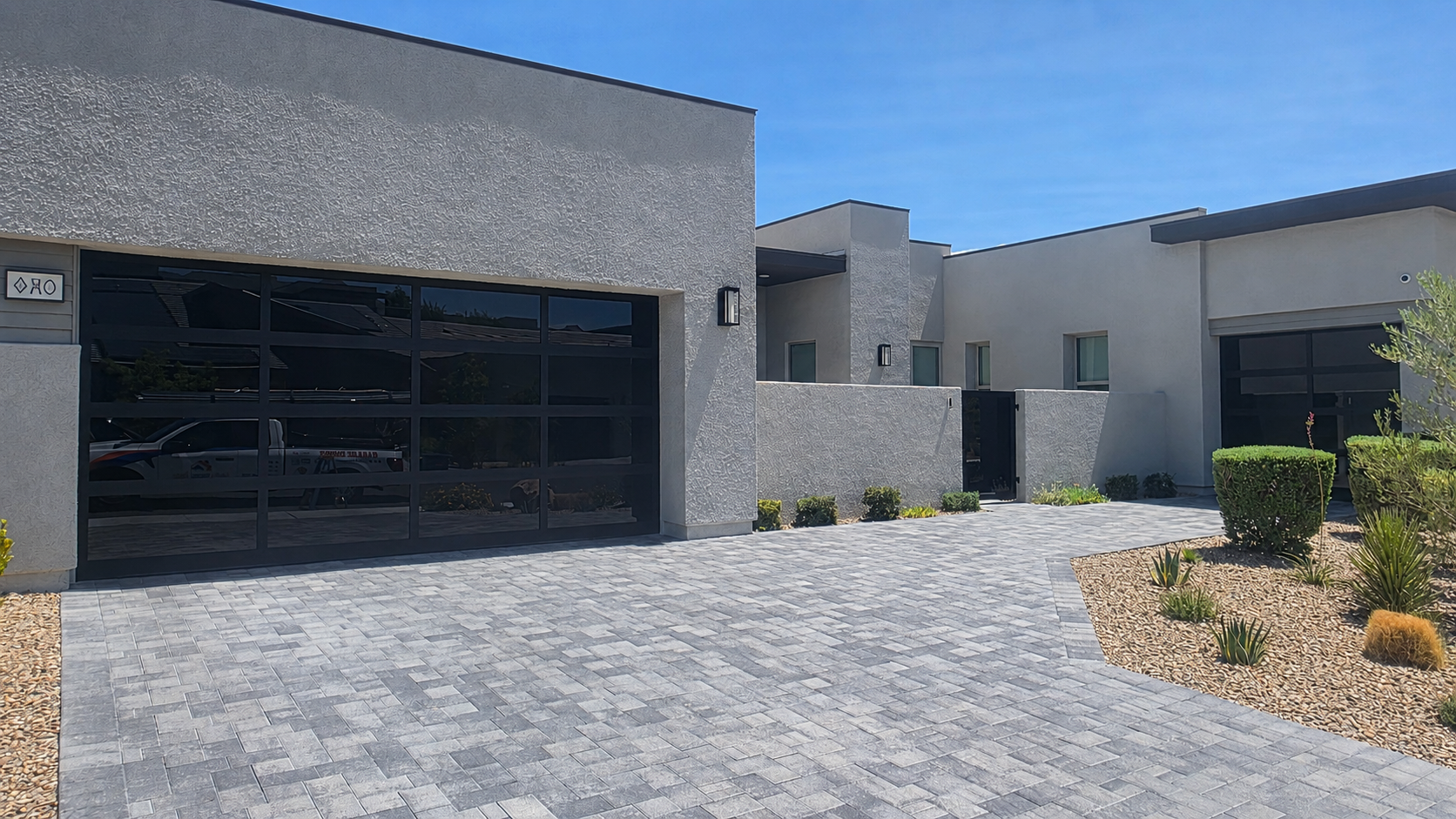Modern full-view aluminum garage door with blackout glass installed on a contemporary home